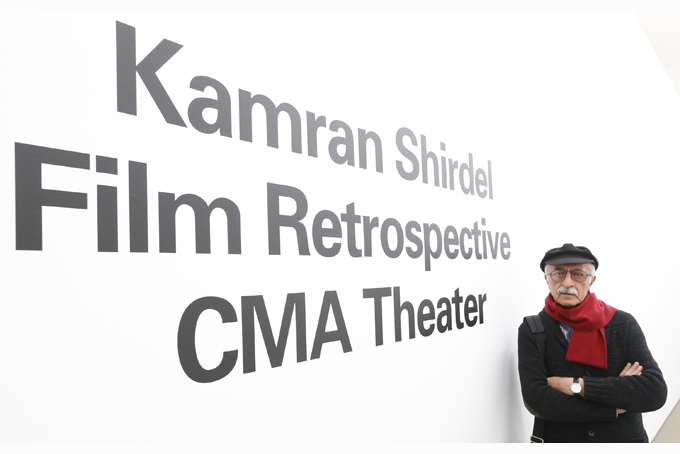 Iranian filmmaker Kamran Shirdel poses beside the sign pointing to where some of his films can be seen at the Carnegie Museum of Art Thursday, Feb. 20, 2014, during his first visit to the U.S. Shirdel began making gritty films of taboo subjects in the 1960s. (AP Photo/Keith Srakocic)
