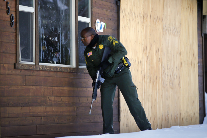 In this Sunday, Feb. 10, 2013, file photo, San Bernardino County Sheriff's officer Ken Owens searches a home for the former Los Angeles police officer Christopher Dorner in Big Bear Lake, Calif. (AP Photo/Jae C. Hong, File)