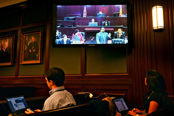 Members of the media monitor the jury selection progress while Cory Strolla, defense attorney for Michael Dunn, on screen second right, questions prospective jurors while State Attorney Angela Corey, on screen at second left, Wednesday, Feb. 5, 2014 in Jacksonville, Fla. (AP Photo/The Florida Times-Union, Bob Mack)