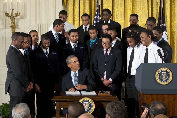 President Barack Obama, center, looks up at students before signing a memorandum creating and expanding ladders of opportunity for boys and young men of color, Thursday, Feb. 27, 2014, in the East Room of the White House in Washington. The White House is partnering with businesses, nonprofits and foundations to address disparities in education, criminal justice and employment. (AP Photo/Pablo Martinez Monsivais)