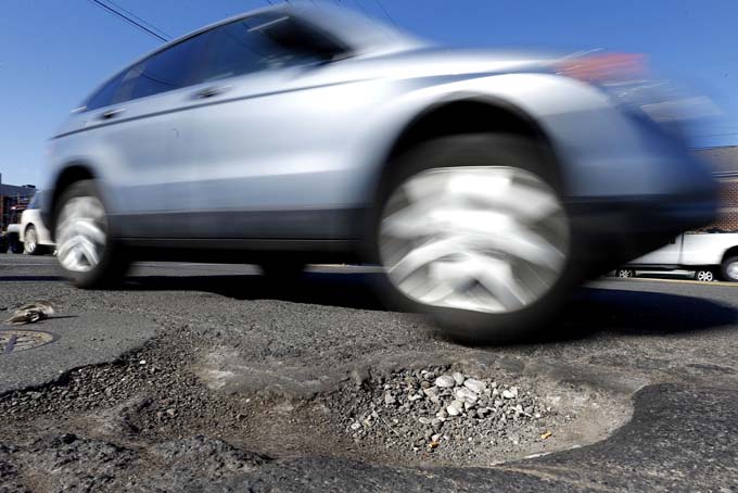 A vehicles drives past a pothole in Philadelphia on Monday, Feb. 24, 2014. Since Dec. 1, 2013, PennDOT workers have applied more than 2,000 tons of patching material in the five counties around the city, according to spokesman Gene Blaum. (AP Photo/Matt Rourke)