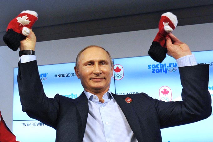 Russian President Vladimir Putin shows handmade mittens presented to him at Canada House during the 2014 Winter Olympics, Friday, Feb. 14, 2014 in Sochi, Russia. At left is Chairman of the Canadian National Olympic Committee Marcel Aubut. (AP Photo / RIA-Novosti, Mikhail Klimentyev, Presidential Press Service)