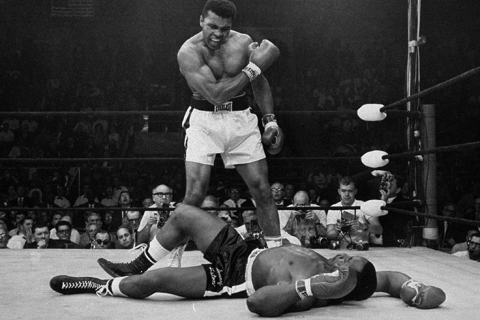 In this May 25, 1965 file photo, heavyweight champion Muhammad Ali stands over fallen challenger, Sonny Liston, shortly after dropping him with a short hard right to the jaw in Lewiston, Maine. In 1964 he changed his name from Cassius Clay and adopted his Muslim name. (AP Photo/John Rooney)