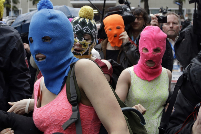 Russian punk group Pussy Riot members Nadezhda Tolokonnikova, in the blue balaclava, and Maria Alekhina, in the pink balaclava, make their way through a crowd after they were released from a police station, Tuesday, Feb. 18, 2014, in Adler, Russia. (AP Photo/Morry Gash)