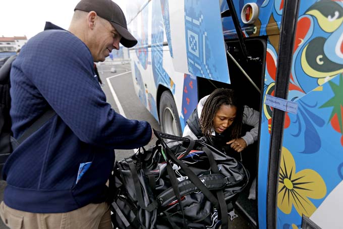 United States women's bobsled head coach Todd Hays, left, helps brakeman Lauryn Williams from Rochester, Pa., also a gold medalist in the 4x100-meter relay at the 2012 London Summer Olympics, load luggage into a waiting bus as the team arrives for the 2014 Winter Olympics, Thursday, Jan. 30, 2014, in Sochi, Russia. (AP Photo/David Goldman, Pool)