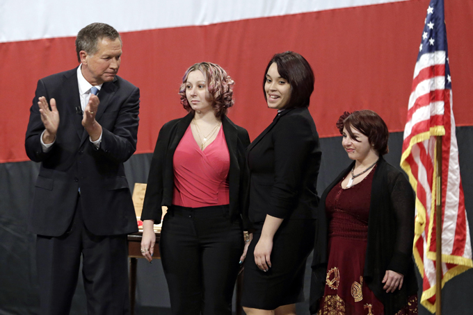 Ohio Gov. John Kasich, from left, introduces Amanda Berry, Gina DeJesus and Michelle Knight during his State of the State address at the Performing Arts Center Monday, Feb. 24, 2014, in Medina, Ohio. (AP Photo/Tony Dejak)