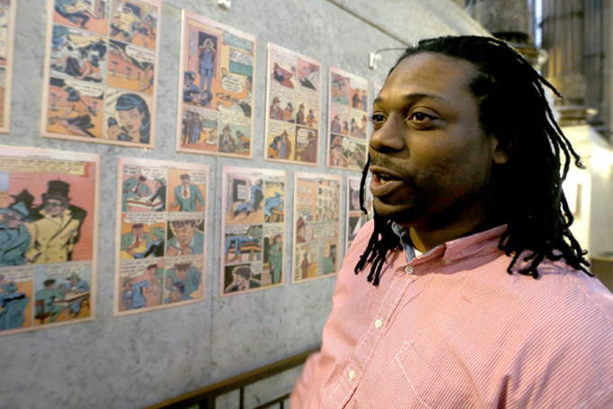 In this Feb. 5, photo, Chay Tyler stands near the pages from the single issue of “All-Negro Comics” published by Orrin Evans in 1947 on display at the City/County building in downtown Pittsburgh. (AP Photo/Keith Srakocic)