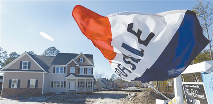 NEW HOME SALES—In this Thursday, Jan. 8 photo, a flag flaps in the breeze in front of a new home for sale in Richmond, Va. The Commerce Department reports on sales of new homes for December on Tuesday, Jan. 27. (AP Photo/Steve Helber) 
