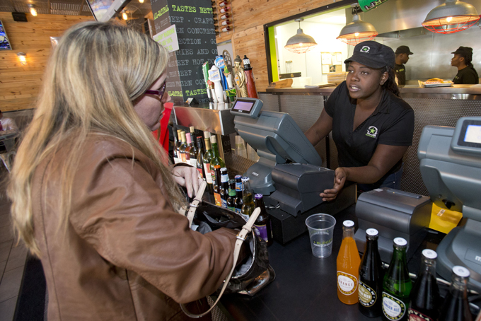 In this Tuesday, Jan. 27, 2015 photo, BurgerFi restaurant supervisor Alexis Charles, right, takes an order from Ellisa Horvath of Aventura, Fla., at the restaurant in Aventura. (AP Photo/Wilfredo Lee)