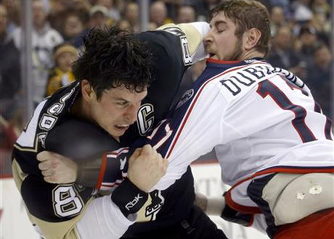 Pittsburgh Penguins' Sidney Crosby, left and Columbus Blue Jackets' Brandon Dubinsky are seen through the dasher board glass as they exchange blows in a fight in the second period of an NHL hockey game, Thursday, Feb. 19, 2015 in Pittsburgh. (AP Photo/Keith Srakocic)