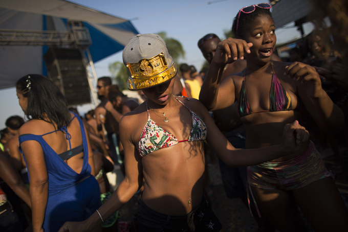 In this Jan. 20, 2015 photo, Viviane Nascimento, 27, wearing a cap covered with the word "money" dances samba at the artificial beach Piscinao de Ramos or “Big Pool of Ramos” in Rio de Janeiro, Brazil. A spate of mass robberies by groups of youths are keeping poorer Rio residents closer to home, on an artificial shoreline built on the banks of trash-strewn and polluted Guanabara Bay. (AP Photo/Leo Correa)
