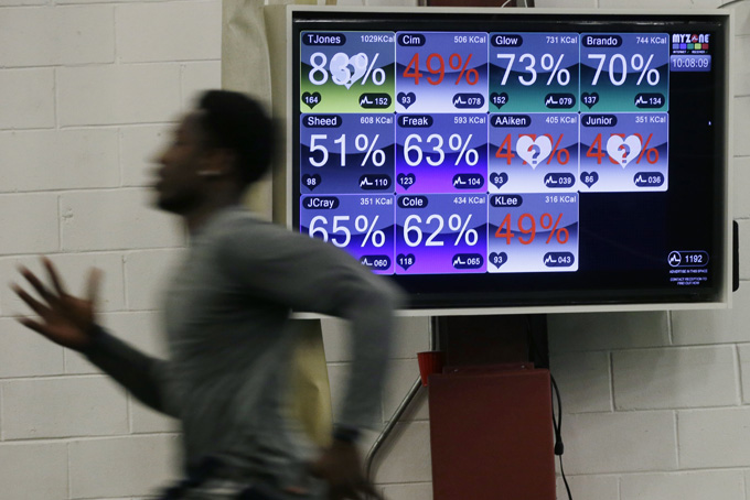 In this Feb. 16, 2015, photo a college football player runs near a large screen displaying data from monitors attached to each player at TEST Parisi Football Academy in Martinsville, N.J. Players are training at the facility for the NFL scouting combine in Indianapolis this week. (AP Photo/Mel Evans)