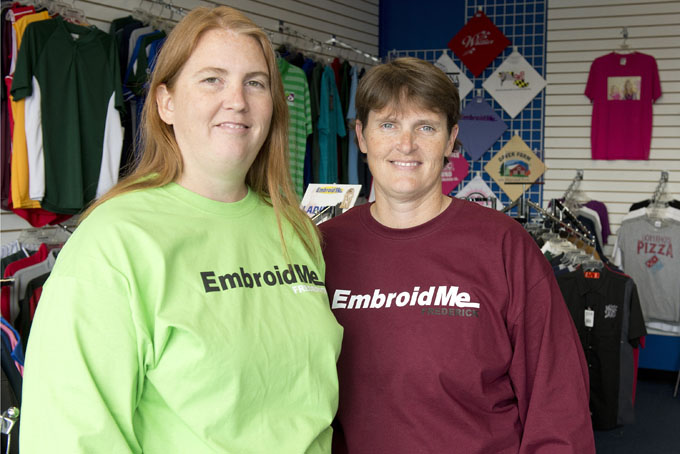 This photo taken Feb. 6, 2015, shows Amy Phillips, left and Angie Foster, owners of EmbroidMe in Frederick who moved to Frederick from their home in North Carolina in search of a school that would provide the best deaf-centric learning environment for their son Seth, who is hard of hearing. (AP Photo/Frederick News-Post, Bill Green)