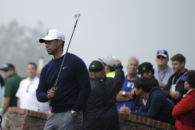 Tiger Woods takes a few one-arm swings during a fog delay while waiting to tee off during the first round of the Farmers Insurance Open golf tournament Thursday, Feb. 5, 2015, in San Diego. (AP Photo/Gregory Bull)