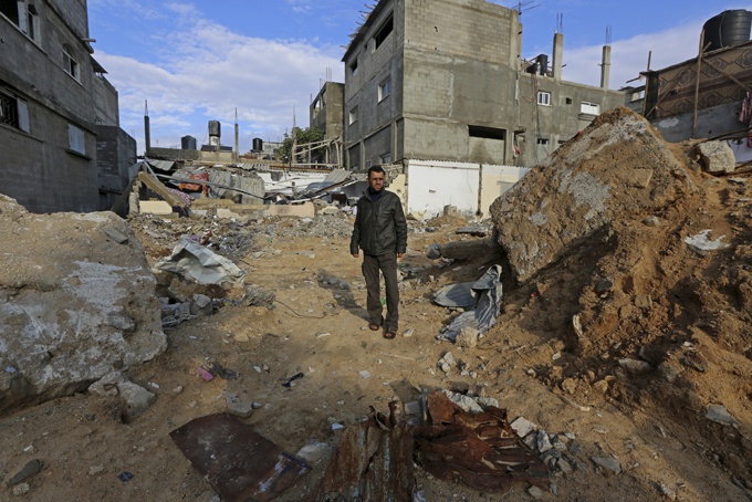 In this Tuesday, Nov. 25, 2014 photo, Mohammed Abu Nijem, 37, stands on the rubble of his family building destroyed by an Israeli airstrike in Jebaliya refugee camp in the northern Gaza Strip. The Aug. 3 attack killed his eight family members, including a 92-year-old uncle, and two senior members of the militant Islamic Jihad group. During last summer’s Gaza war with Hamas, Israel targeted scores of homes it said were used for military purposes. Palestinians say Israeli warplanes often struck without regard for civilians. (AP Photo/Adel Hana)