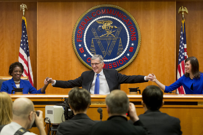 Federal Communication Commission (FCC) ChairmanTom Wheeler, center, joins hands with FCC Commissioners Mignon Clyburn, left, and Jessica Rosenworcel, before the start of their open hearing in Washington, Thursday, Feb. 26, 2015. Internet service providers like Comcast, Verizon, AT&T, Sprint and T-Mobile would have to act in the "public interest" when providing a mobile connection to your home or phone, under new rules being considered by the Federal Communications Commission. The rules would put the Internet in the same regulatory camp as the telephone, banning providers from "unjust or unreasonable" business practices. (AP Photo/Pablo Martinez Monsivais)