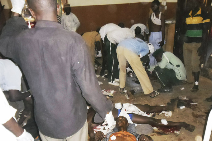 In this photo taken Sunday, Feb. 22, 2015, people help those injured by a bomb at a local hospital in Potiskum in northeastern Nigeria.  (AP Photo/Adamu Adamu)