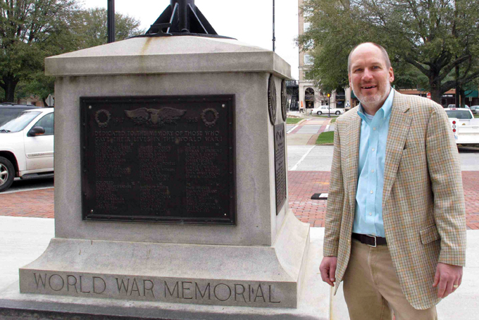 In this Jan. 22, 2015 photo, Greenwood Mayor Welborn Adams stands beside the Greenwood County memorial in Greenwood, S.C.,  that honors its citizens who died in recent wars. The World War I and World War II soldiers are separated into colored and white. Adams raised $15,000 to put new plaques on the statue, but a state law won't allow him to put them up. (AP Photo/Jeffrey Collins)