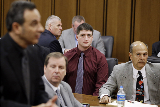 In this Dec. 17, 2014 photo, suspended Cleveland Police patrolman Michael Brelo, center, watches during a court hearing in Cleveland. A motion filed Tuesday, March 10, 2015, asks a Cuyahoga County judge in Cleveland to dismiss two voluntary manslaughter charges against 30-year-old Brelo. (AP Photo/Tony Dejak)