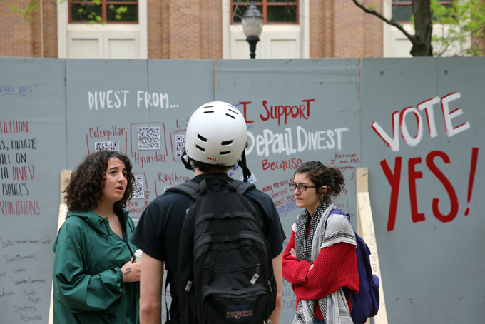 In this Tuesday, May 13, 2014 photo, Dina Abdalla, left, and Leila Abdul Razzaq, of Students for Justice in Palestine, talk to a fellow student in front of an "apartheid wall" their group created to promote voting for divestment at DePaul University in Chicago. (AP Photo/Chicago Tribune, Brian Cassella)