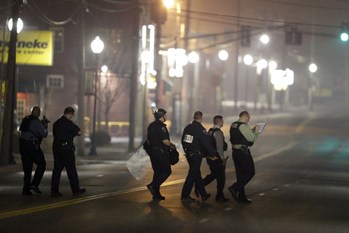 Police canvass the area as they investigate the scene where two police officers were shot outside the Ferguson Police Department Thursday, March 12, 2015, in Ferguson, Mo. (AP Photo/Jeff Roberson)