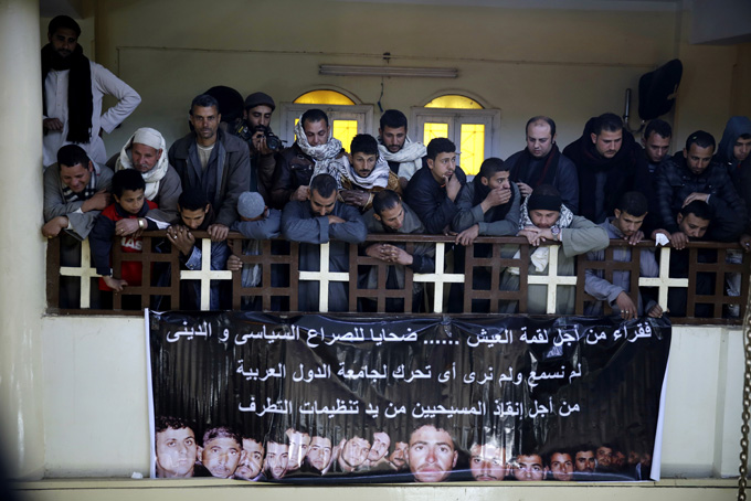 A man mourns over Egyptian Coptic Christians who were captured in Libya and killed by militants affiliated with the Islamic State group, inside the Virgin Mary Church in the village of el-Aour, near Minya, 220 kilometers (135 miles) south of Cairo, Egypt, Monday, Feb. 16, 2015. Egyptian warplanes struck Islamic State targets in Libya on Monday in swift retribution for the extremists' beheading of a group of Egyptian Christian hostages on a beach, shown in a grisly online video released hours earlier. The banner in Arabic reads, "poor for a piece of bread.. Victims of political and religious conflict, we did not hear nor see any reactions from Arab nations to save the lives of these Christians from the hands of extremists. " (AP Photo/Hassan Ammar)