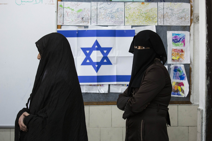FILE - In this Tuesday, March 17, 2015 file photo, Bedouin women wait to cast their votes at a polling station in the town of Rahat, Israel on for parliament elections. After a strong performance in last week’s parliamentary election, Prime Minister Benjamin Netanyahu seems to be cruising toward forming a new government of hardline and religious parties. But in the smoke-and-mirrors world of Israeli politics, a centrist government more amenable to peace negotiations could easily emerge at the last minute instead. (AP Photo/Tsafrir Abayov, File)