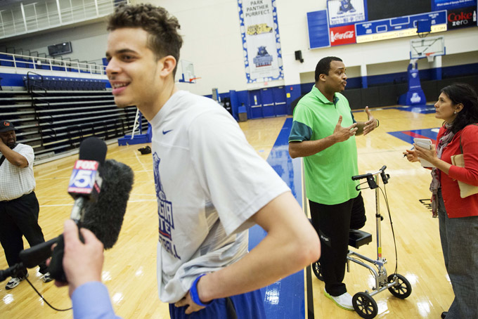 Georgia State men's head basketball coach Ron Hunter, right, and his son and team member, R.J. Hunter, left, talk to reporters Monday, March 16, 2015, in Atlanta. Georgia State is heading to the NCAA Tournament, but Hunter's got to figure out a way to coach the Panthers with his left leg in a cast after a freak injury at the end of the team's win in the Sun Belt Conference championship game. One of the country's most animated coaches, Hunter leaped off the bench when Georgia Southern's final shot bounced off the rim. He then felt a sharp pain in his left leg, "like I'd been shot." His Achilles tendon was torn. For now, Hunter is getting around on a four-wheeled scooter, pushing the device with his right leg. (AP Photo/David Goldman)
