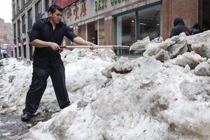 In this March 4, 2015 file photo, waiter Melvin Angel shovels snow outside the restaurant he works at in the Chinatown neighborhood of Boston. Every work day lost during New England’s historic winter has meant millions of dollars out of the regional economy. Retailers and restaurants were among the hardest hit, but hotels, transportation companies and other tourism businesses struggled too. (AP Photo/Charles Krupa)