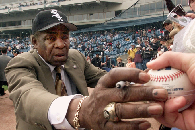 In a April 6, 2001 file photo, Chicago White Sox legend Orestes "Minnie" Minoso signs autographs prior to the Sox' home opener against the Detroit Tigers, at Comiskey Park in Chicago. Major league baseball's first black player in Chicago, Minnie Minoso, has died. The Cook County medical examiner confirmed his death Sunday, March 1, 2015. There is some question about his age but the White Sox say he was 92. (AP Photo/Ted S. Warren, File)