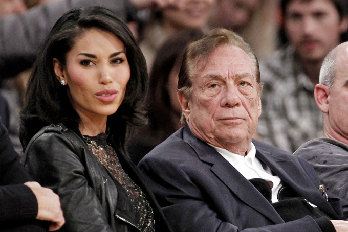 In this Dec. 19, 2011, file photo, Los Angeles Clippers owner Donald Sterling, right, sits with V. Stiviano as they watch the Clippers play the Los Angeles Lakers during an NBA preseason basketball game in Los Angeles. Sterling's wife, Shelly Sterling, is going after the $2.5 million in real estate and cars her husband lavished on V. Stiviano in a trial scheduled to begin Wednesday, March 25, 2015, in Los Angeles Superior Court. (AP Photo/Danny Moloshok, File)