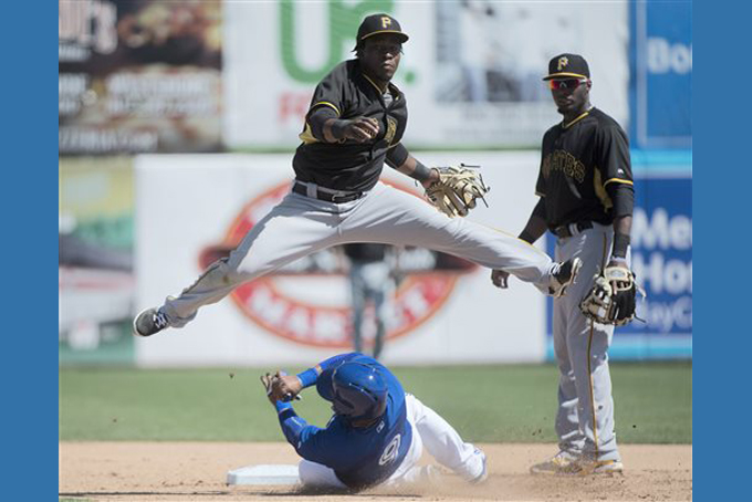 Pittsburgh Pirates shortstop Gift Ngoepe, top, forces out Toronto Blue Jays infielder Santiago Ramon (9) at second base then turns the double play to force Blue Jays Chris Colabello out at first during seventh inning Grapefruit League spring baseball action in Dunedin, Fla., on Sunday, March 8, 2015. (AP Photo/The Canadian Press, Nathan Denette)