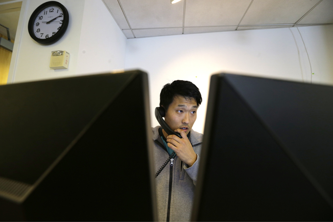Matt Kim an accountant with Gravity Payments, a credit card payment processor based in Seattle, talks on the phone as he works at his desk Wednesday, April 15, 2015.  (AP Photo/Ted S. Warren)