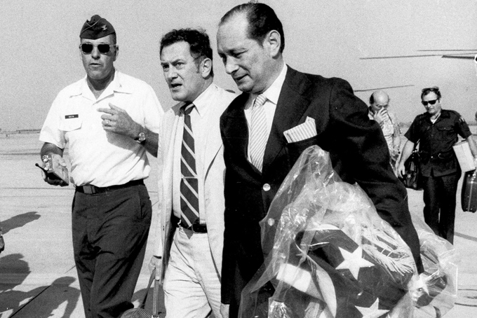 In this April 12, 1975, file photo, U.S. Ambassador to Cambodia John Gunther Dean carries the American flag from the U.S. Embassy in Cambodia as he arrives at Utapao Air Force Base in Thailand following the evacuation from Phnom Penh by helicopter and aircraft carrier. It’s 40 years later, 6,000 miles away and Dean is recalling what he describes as one of the most tragic days of his life - April 12, 1975, the day the United States "abandoned Cambodia and handed it over to the butcher." (AP Photo/Sal Veder, File)