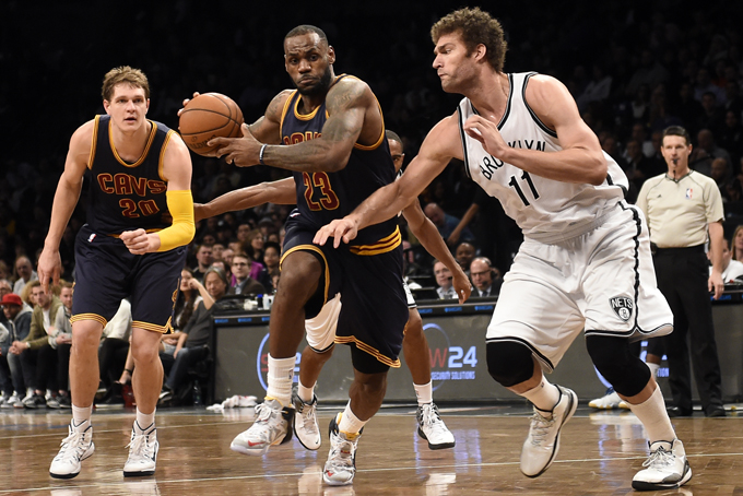 Cleveland Cavaliers forward LeBron James (23) drives the ball around Brooklyn Nets center Brook Lopez (11) as Cavaliers center Timofey Mozgov (20) defends from behind in the first half of an NBA basketball game on Friday, March 27, 2015, in New York. The Nets won 106-98. (AP Photo/Kathy Kmonicek)