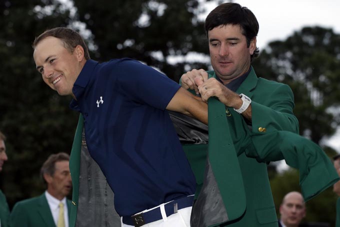 Bubba Watson helps Jordan Spieth put on his green jacket for the second time after winning the Masters golf tournament Sunday, April 12, 2015, in Augusta, Ga. (AP Photo/Darron Cummings)