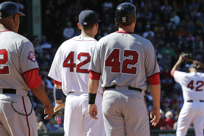 With all players and coaches wearing #42 in remembrance of Jackie Robinson, Boston Red Sox relief pitcher Anthony Varvaro, right, sets to pitch during a baseball game at Fenway Park in Boston, Wednesday, April 15, 2015. Robinson broke Major League Baseball's color barrier on April 15, 1947, taking the field as the first African-American player for the Brooklyn Dodgers. From left are Nationals first base coach Tony Tarasco, Red Sox first baseman Mike Napoli, Nationals base runner Tyler Moore and Varvaro. (AP Photo/Charles Krupa)