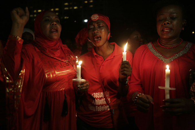 People hold candles as they sing during a vigil to mark the one year anniversary of the abduction of girls studying at the Chibok government secondary school, Abuja, Nigeria, Tuesday, April 14, 2015. (AP Photo/Sunday Alamba)