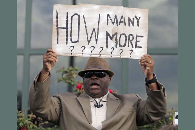 Rev. Arthur Prioleau holds a sign during a protest in the shooting death of Walter Scott at city hall in North Charleston, S.C., Wednesday, April 8, 2015. Scott was killed by a North Charleston police officer after a traffic stop on Saturday. The officer, Michael Thomas Slager, has been charged with murder. (AP Photo/Chuck Burton)