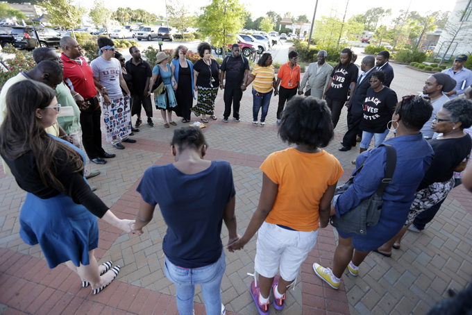 People hold hands in prayer during a rally for the killing of Walter Scott by a North Charleston police officer Saturday, after a traffic stop in North Charleston, S.C., Thursday, April 9, 2015. The officer, Michael Thomas Slager, has been fired and charged with murder. (AP Photo/Chuck Burton)