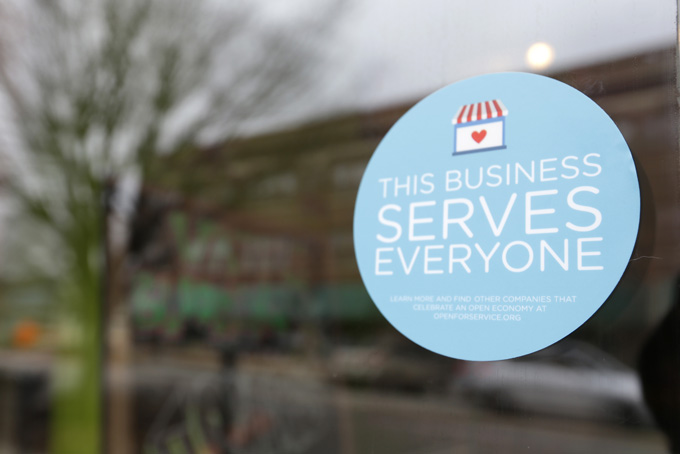 In this March 25, 2015 file photo, a window sticker promising service to all is displayed in opposition to the state new religious objections law in downtown Indianapolis. Tourism agencies in Indianapolis and Fort Wayne are rolling out campaigns to tout the fact that “All Are Welcome” in Indiana, but it might not be enough to completely heal the black eye the state received over its nationally-criticized religious objections law. (AP Photo/Michael Conroy, File)