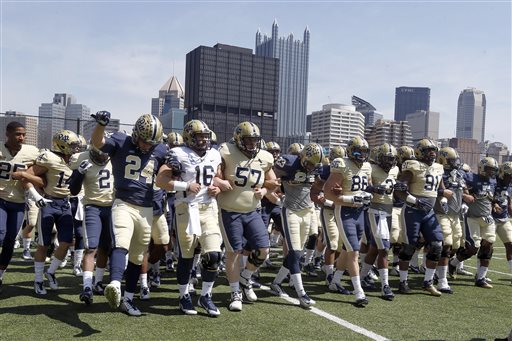 The Pittsburgh football team links arms as they take the field with the city skyline behind them before their NCAA college Blue Gold spring football game, Saturday, April 18, 2015, in Pittsburgh. (AP Photo/Keith Srakocic)