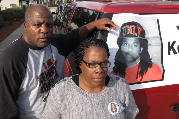 In this Dec. 13, 2013 file photo, Kenneth and Jacquelyn Johnson stand next to a banner on their SUV showing their late son, Kendrick Johnson in Valdosta, Ga. Long after Johnson was found dead inside a rolled-up gym mat at his high school in south Georgia, those closest to the case remain deeply divided over how the teenager died. (AP Photo/Russ Bynum, File)