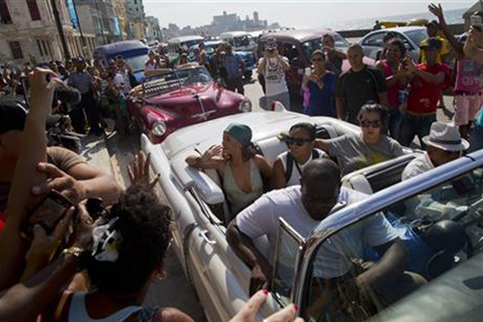 Fans take photographs of pop artist Rihanna, center, as she rides on an American classic car after a photo shoot with photographer Annie Leibovitz at a building on the Malecon, in Havana, Cuba, Friday, May 29, 2015. (AP Photo/Desmond Boylan)