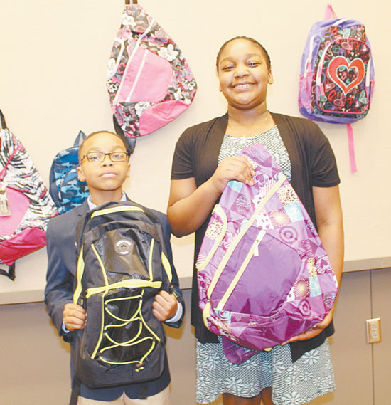 HAPPY RECIPIENTS—Torrien Perkins, 8, and Samaree Perkins, 10,  receive their new backpacks filled with school supplies. 