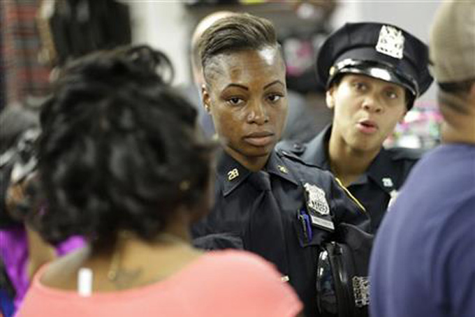 Police officers Shakara President, center, and Lanora Moore talk with an unhappy customer inside a store on 125th Street in the Harlem section of New York, Wednesday, April 29, 2015. (AP Photo/Seth Wenig)