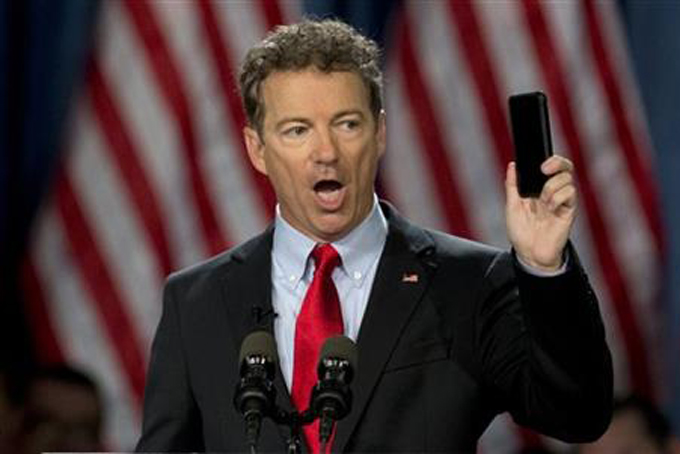  In this April 7, 2015 file photo, Sen. Rand Paul, R-Ky. holds up his cell phone as he speaks before announcing the start of his presidential campaign, in Louisville, Ky. The Justice Department warned lawmakers that the National Security Agency (NSA) will have to wind down its bulk collection of Americans' phone records by the end of the week if Congress fails to reauthorize the Patriot Act. The Republican divisions over the issue was on stark display in the Senate on Wednesday as Paul, a candidate for president, stood on the floor and spoke at length about his opposition to NSA spying. (AP Photo/Carolyn Kaster, File)