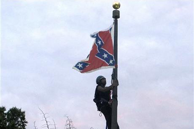 Bree Newsome of Charlotte, N.C., climbs a flagpole to remove the Confederate battle flag at a Confederate monument in front of the Statehouse in Columbia, S.C., on Saturday, June, 27, 2015.  (AP Photo/Bruce Smith)