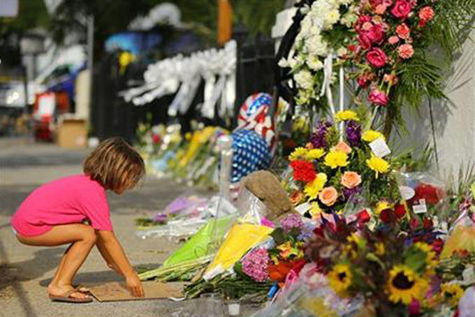 Lydia Blessing, 4, places a hand written note at a memorial in front of the Emanuel AME Church on Friday, June 19, 2015 in Charleston, S.C. Dylann Storm Roof, 21, is accused of killing nine people during a Wednesday night Bible study at the church. ( Curtis Compton/Atlanta Journal-Constitution via AP) 