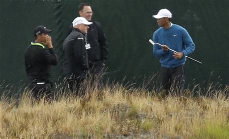 Golfer Tiger Woods, right, walks past a fence as rain begins to fall, Tuesday, June 2, 2015, as he took practice shots at Chambers Bay in University Place, Wash., where the U.S. Open will be played June 18-21, 2015. (AP Photo/Ted S. Warren)